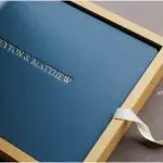 A Navy Blue Leather Album rests in a two toned Gold and blue case.