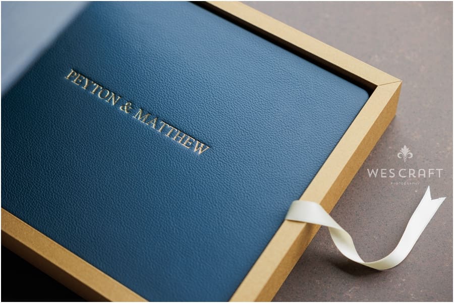A Navy Blue Leather Album rests in a two toned Gold and blue case.