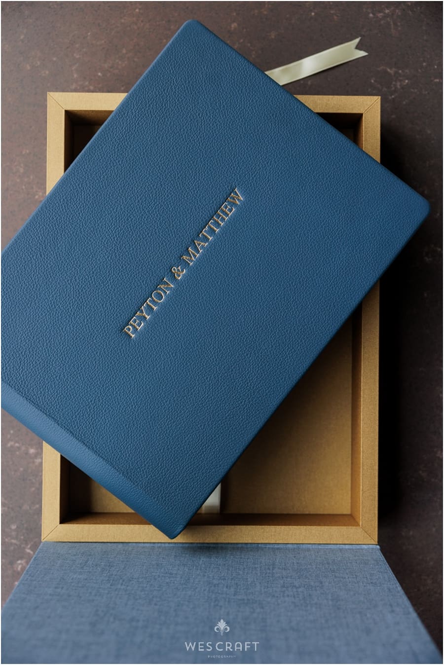 A Navy Blue Leather Album rests in a two toned Gold and blue case.